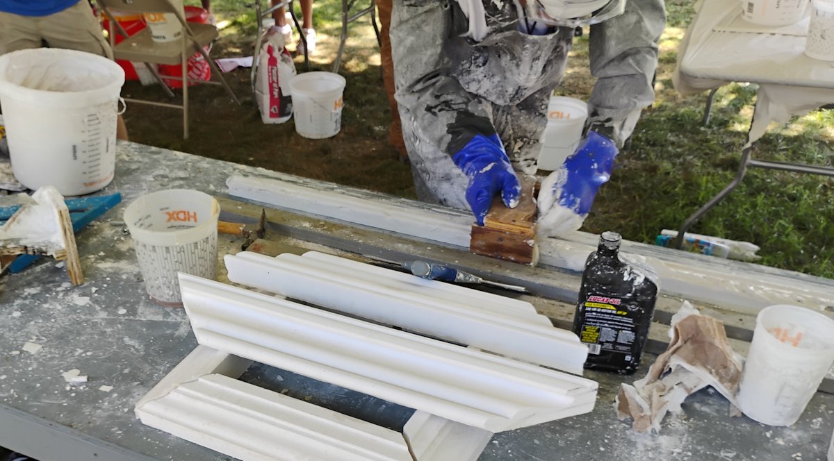 A plasterer runs a molding on a bench at the Smithsonian Folklife Festival in Washington, DC.
